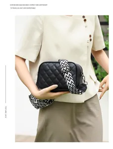 Black leather quilted crossbody bag for women with chic patterned wide strap detail.
