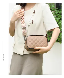 Khaki quilted leather crossbody bag featuring a stylish wide patterned strap and compact design.