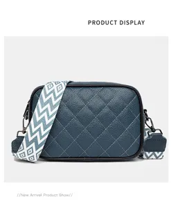 Dark blue quilted leather crossbody bag with wide geometric strap, chic fashion style.