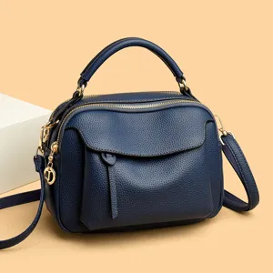 Blue soft leather crossbody bag with top handle, double zippers and stylish front pocket design.