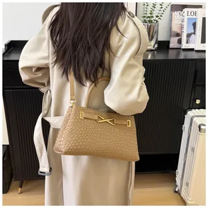 Detail shot of the stylish woven leather handbag with metal clasp and top handle. Elegant accessory.