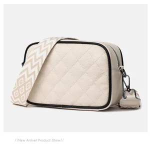 Close-up detail of the beige quilted leather crossbody camera bag with wide strap.
