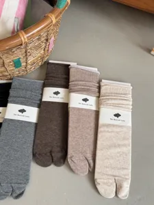 Detailed view of women autumn solid color mid tube split toe slouchy socks in neutral shades.
