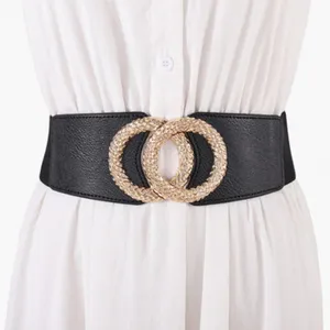 Detalle de cinturón elástico ancho negro con hebilla redonda dorada trenzada en vestido.