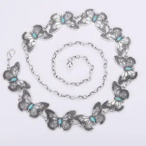 Detalle de cadena de cintura de mariposa con eslabones de metal plateado y piedra turquesa para vestido.