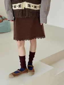 Vue détaillée de jambières côtelées marron rétro associées à une jupe en velours et des chaussures.