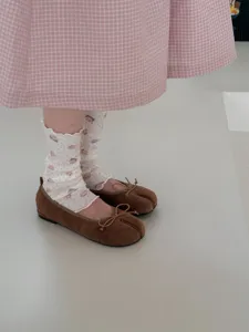 Gros plan de chaussettes blanches à volants ornées de motifs d'ours avec des ballerines.