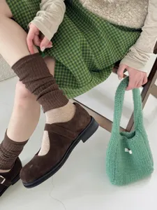 Vue détaillée de chaussettes marron rétro associées à des chaussures Mary Jane et un sac vert.