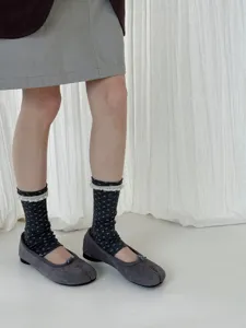 Close-up shot showing dark floral socks with delicate white lace trim paired with grey tabi shoes.