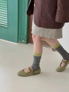 Detail shot showing striped stirrup socks with retro Mary Jane shoes in a chic lifestyle setting.