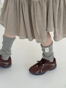 Knit leg warmers detail shot showing soft gray texture, paired with retro sneakers.
