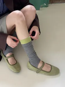 Close-up detail of women's color-block striped stirrup socks paired with green Mary Jane shoes.