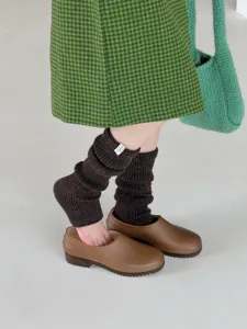Merino wool knitted leg warmers detail, thick warm winter cozy slouch socks close-up view.