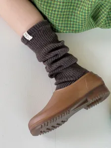 Close-up detail of cozy brown knit wool slouch socks, soft textured winter warm leg warmers.
