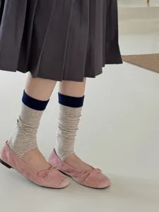 Close-up detail shot of women's striped stirrup slouch socks paired with pink flat shoes.