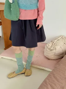 Detail shot of Korean style color-block dot leg warmers layered with cozy knit outfit.