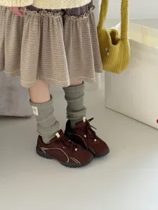 Detailed view of cozy knit slouch socks paired with retro sneakers and striped skirt.