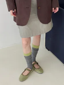 Detailed close-up showing striped stirrup socks paired with green shoes, casual style.