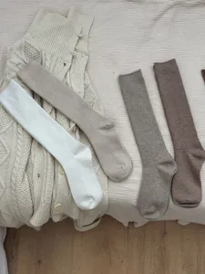 Detail view of cozy knit wool calf socks in versatile neutral colors like white, grey and brown.