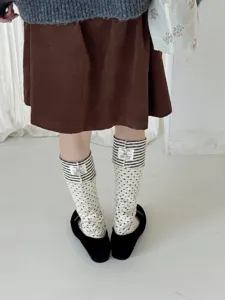 Detailed close-up of Korean style color contrast layered stirrup socks with cute polka dot patterns.