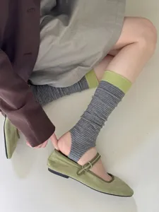 Detailed shot of striped stirrup socks paired with green shoes, showing texture and fit.