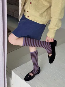 Detailed shot of retro striped long socks in purple and brown, paired with flat shoes.