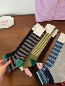 Detailed shot of Korean-style contrast color striped long socks with cozy ribbed cuffs.