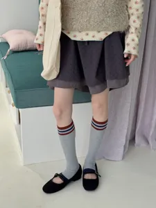 Trendy grey striped tube socks matched with black Mary Jane shoes for cozy autumn retro daily styles.