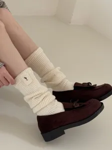 Close-up detail of cozy knit wool slouch socks paired with brown loafers for autumn fashion.