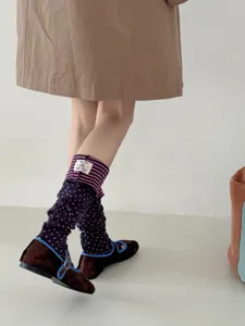 Detailed shot of retro polka dot leg warmers paired with velvet shoes. Elegant style.