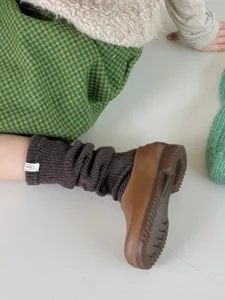 Close-up detail of dark brown wool knit leg warmers showing soft texture and cozy winter style.