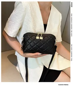 Detail view of the black quilted leather crossbody bag with chic gold zippers and strap.