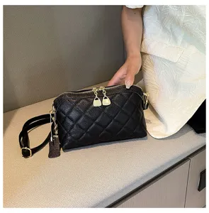 Detailed view of black quilted leather crossbody bag with metallic zipper and elegant strap.