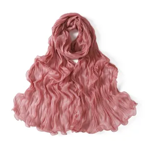 Close-up detail view of crinkled sheer tulle scarf texture, soft pleated lightweight fabric.
