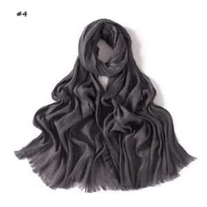 Crinkled scarf detail showing fine texture, elegant dark grey fabric and delicate fringe edges.