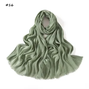 Detailed view of the sage green crinkled scarf with stylish fringed edges and soft drape.