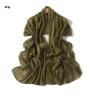 Close-up detail of the olive green metallic chiffon scarf showing fine pleats and shimmering texture.
