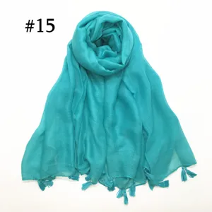 Detail view of lightweight turquoise voile scarf with delicate tassel fringe edges and soft texture.