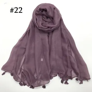 Detail view of a lightweight solid color voile scarf featuring delicate hanging tassels. Perfect