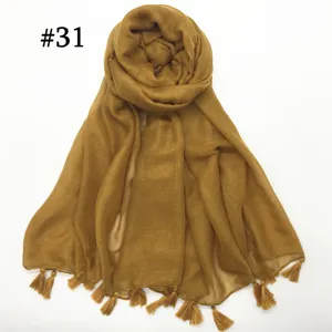 Detailed shot of lightweight solid mustard yellow voile scarf with delicate tassel fringe.