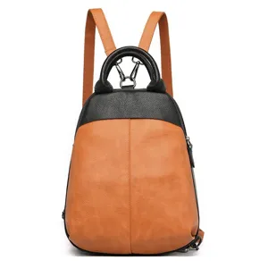 Detailed view of the dual-tone leather backpack showing the metal handle rings and secure hardware.
