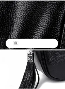 Close-up detail of black genuine leather women bag texture with tassel zipper pull.
