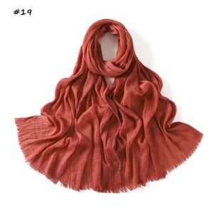 Detailed view of solid color crinkled scarf with tassel fringe, breathable fashion accessory.