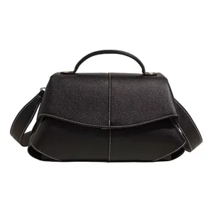 Vue détaillée du sac à main noir en cuir avec poignée et coutures blanches contrastées.