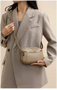 Detail view of the khaki genuine leather crossbody bag with dual zippers and fine strap.