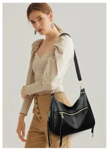 Detail view of a black hobo shoulder bag with gold zippers, tassels, and spacious interior.