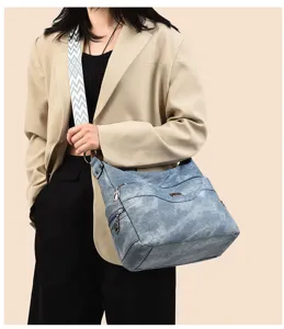 Detailed view of the blue washed PU leather shoulder cross-body bag worn by a model gracefully.