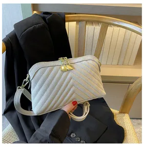 Detailed shot of chevron quilted leather crossbody bag in light grey with gold hardware.