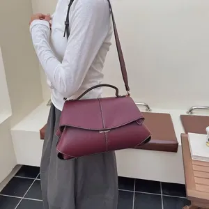 Vue détaillée du sac à épaule bordeaux en cuir élégant avec design plié et coutures blanches.