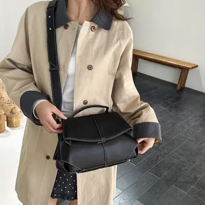 Vue rapprochée d'un sac à main noir tendance avec surpiqûres et bandoulière réglable.